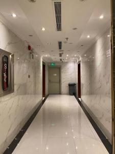 a hallway with white marble walls and a door at فندق منازل قباء الفندقية in Medina