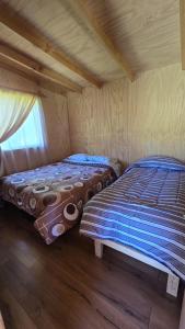 two beds in a small room with a window at Casa de campo in Lago Ranco