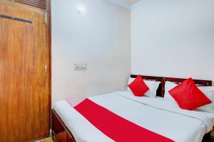 a bedroom with a bed with red pillows on it at Hotel O Ratiram in Kalkaji Devi