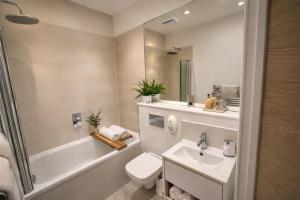 a bathroom with a sink and a toilet and a tub at Margate Penthouse Private Balconies Sea Glimpses Gated Parking Air-Con The Penthouse Margate in Margate