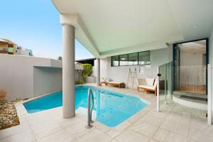 a house with a swimming pool and a patio at La Promenade Absolute Waterfront Apartments in Caloundra