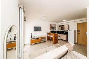 a living room with a couch and a kitchen at Studio Harmonia Ar Cond/Centro/Piscina/Academia in Juiz de Fora