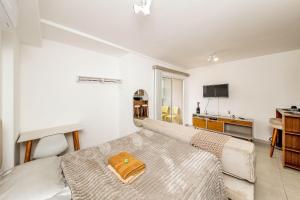 a white room with a bed and a kitchen at Studio Harmonia Ar Cond/Centro/Piscina/Academia in Juiz de Fora