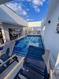a large swimming pool in a building with a chair at Studio Harmonia Ar Cond/Centro/Piscina/Academia in Juiz de Fora
