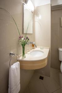 a bathroom with a sink with a vase of flowers at Hotel Del Comahue in Neuquén