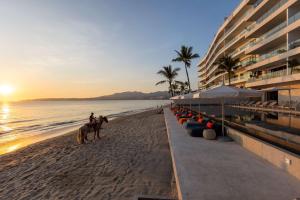 a person riding horses on the beach near a hotel at UDARA - Beachfront Condos in Golden Zone with Rooftop in Bucerías