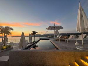 a swimming pool with umbrellas and chairs and the ocean at UDARA - Beachfront Condos in Golden Zone with Rooftop in Bucerías