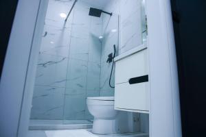 a white bathroom with a toilet and a shower at Amiri Lux Suites in Shkodër +5 photos