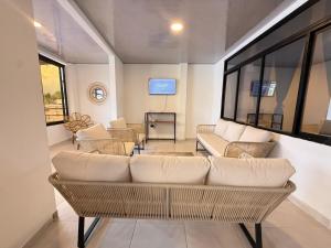 a living room with white furniture and windows at Toba hotel boutique in Ibagué