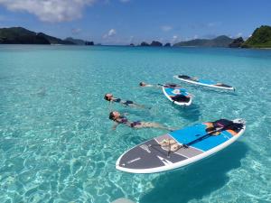 a group of people in the water next to surfboards at Guesthouse Iyonchi in Zamami