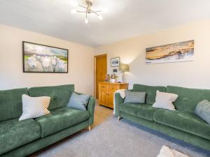 a living room with two green couches at Carrie's Gate in Coniston