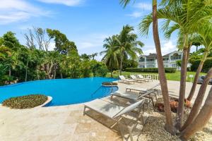 a swimming pool with chairs and palm trees at Royal Apartment 223 in Saint James