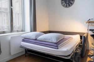 a hospital bed with pillows and a clock on the wall at La petite cour in Beaune