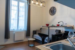a living room with a table and a clock on the wall at La petite cour in Beaune +29 photos