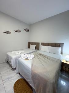 two beds in a hotel room with white sheets at Pousada Cajueiro Do Sol in Barreirinhas +58 photos