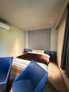 a bedroom with a bed and two blue chairs at Hotel JOYCE in Saijō-chō