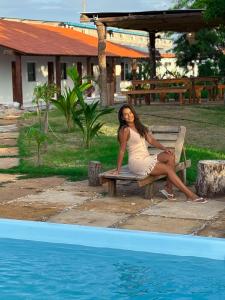 a woman sitting on a bench next to a swimming pool at Pousada Cajueiro Do Sol in Barreirinhas