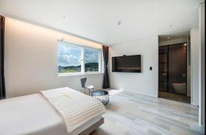 a white bedroom with a bed and a television at Daegu Innovation City Stay22 in Panyawŏl-yŏk