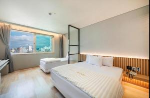 a bedroom with a large white bed and a window at Daegu Innovation City Stay22 in Panyawŏl-yŏk