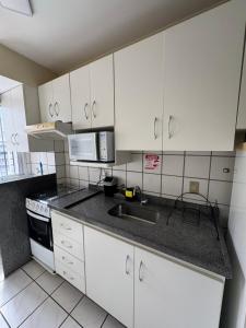 a kitchen with white cabinets and a sink at Apto Aquarius - Piscinas Aquecidas, Hidro e Lazer Total - até 5 Pessoas in Caldas Novas