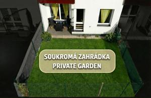 a sign in the grass next to a building at Apartmán Benedikt - soukromá zahrádka in Vrchlabí