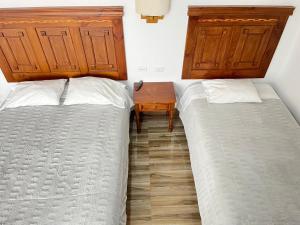 a bedroom with two beds and a wooden table at Aparthotel Cusco in San Antonio