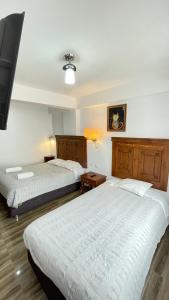 two beds in a hotel room with two beds at Aparthotel Cusco in San Antonio