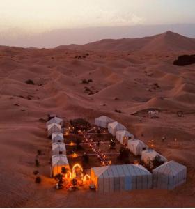an aerial view of a desert with buildings in the desert at Azadic luxury tents in Merzouga +34 photos