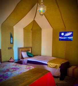 a bedroom with two beds and a chandelier at Azadic luxury tents in Merzouga
