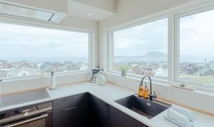a kitchen with a sink and two large windows at Luxury Townhouse with Panoramic Sea View in Tórshavn