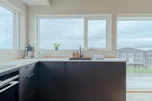 a kitchen with black cabinets and two windows at Luxury Townhouse with Panoramic Sea View in Tórshavn