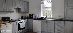 a kitchen with white cabinets and a sink and a window at Clare Cottage in Doolin