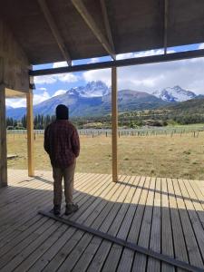 a person standing on a porch looking at the mountains at Refuge with Panoramic Views, Cerro Castillo in Villa Cerro Castillo +7 photos