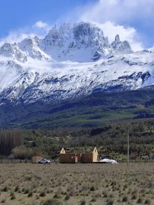 a snow covered mountain with a house in a field at Refuge with Panoramic Views, Cerro Castillo in Villa Cerro Castillo
