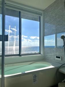 a bathroom with a bath tub with a large window at CHLOROBIANCO amami in Amami