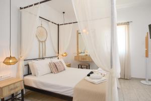 a bedroom with a white bed with a canopy at Louros rooms in Koufonisia