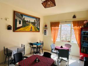 a dining room with tables and chairs and a painting on the wall at Hostal Colombia plaza in San Gil