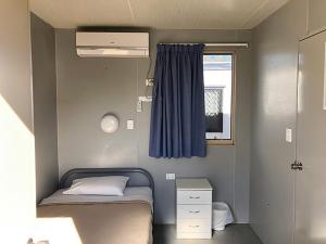 a small bedroom with a bed and a window at The Moonie Crossroads Hotel in Moonie