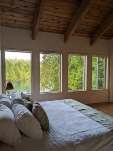 a large bed in a room with three windows at Argo's Landing in Bamfield
