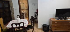 a dining room with a table and chairs and a television at Casa da Massada in Belmonte