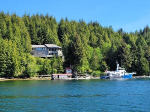 a boat is docked on the water near a house at Argo's Landing in Bamfield