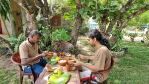 two men sitting at a table eating food at Pasikuda Shalom Echo Villa in Palayadithona