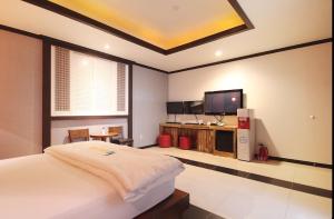a bedroom with a bed and a flat screen tv at Dongdaegu Leaders Hotel in Daegu