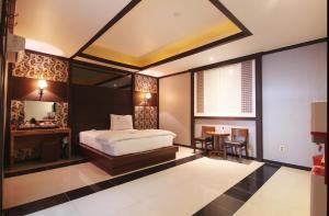 a bedroom with a bed and a table and a window at Dongdaegu Leaders Hotel in Daegu