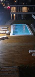 a swimming pool on a wooden deck with chairs around it at Kilka Departamento 3 Ambientes con Balcón in Mar de las Pampas