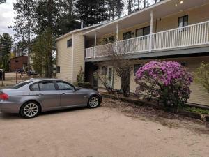 a car parked in front of a house with purple flowers at Condo Ideal location Ski, Shop, Hike in Conway