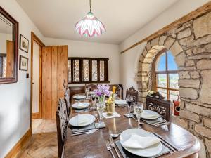 a dining room with a table and a stone wall at The Barn in Keighley