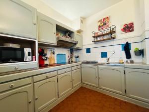 a kitchen with white cabinets and a microwave at Casa Boho in Angers