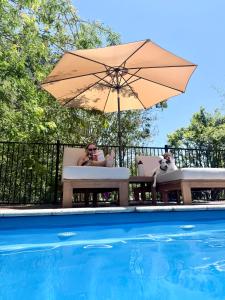 a woman sitting in a chair under an umbrella next to a pool at Wyobie Kangaroo Valley Treehouse in Kangaroo Valley
