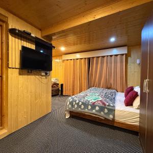 a bedroom with a bed and a flat screen tv at The VILLAGE RESORT ASHUNA in Kargil